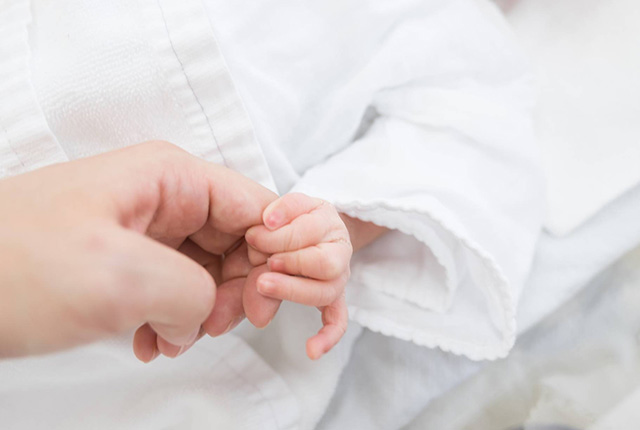 乳児の手を大人が握る様子