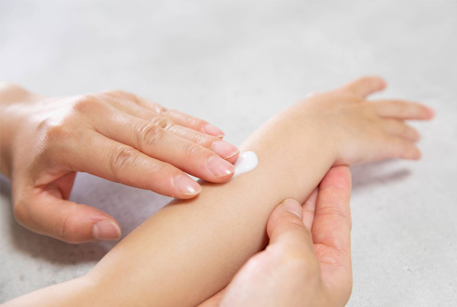 子供の腕にクリームを塗る様子